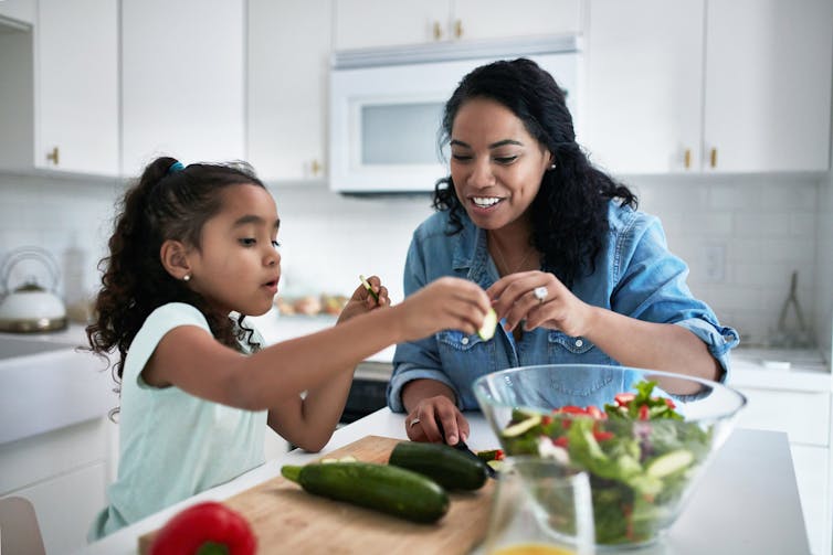 girl and woman prepare vegetables together