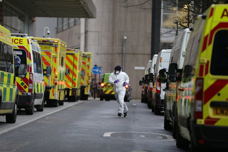 A health worker runs between two rows of ambulances.