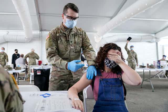 A Florida woman covers her eyes as she receives a COVID-19 vaccine shot