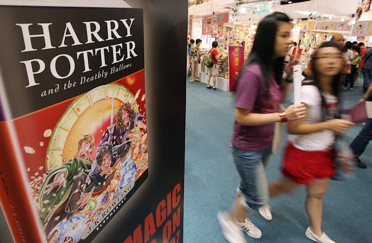 Two teenage girls walking past a Harry Potter book display at a book fair in China.