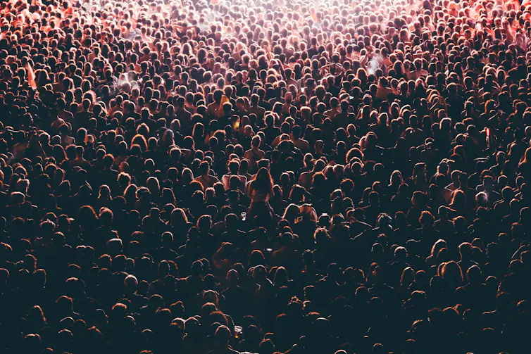 Colorful crowd of people of a big music festival in a stage lights as a beautiful background