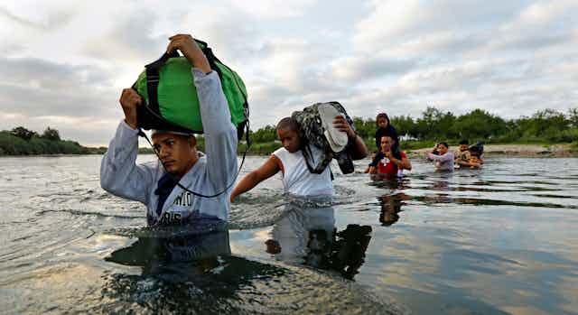 A group of migrants cross the Rio Grande River.