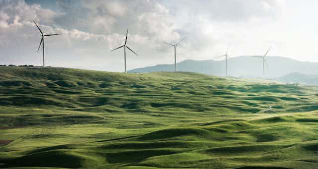 A hilly green field with wind turbines.