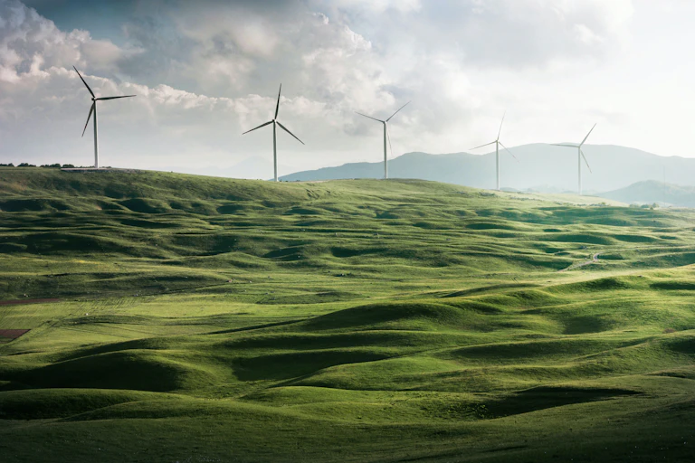 A hilly green field with wind turbines.