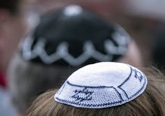 Kippahs are seen atop two heads in a crowd.