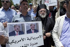 Activists from the Boycott, Divest and Sanctions (BDS) movement chant slogans and carry a placard with defaced pictures of former U.S. president Donald Trump and Arabic that reads: 'American Imperialism is the people's enemy.'