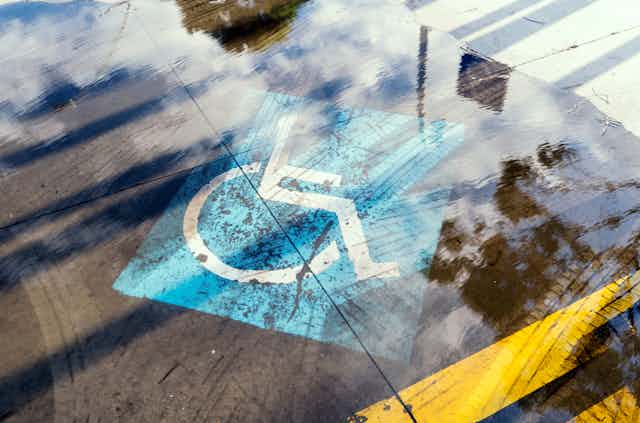 Floodwaters cover a disability sign on a parking spot.