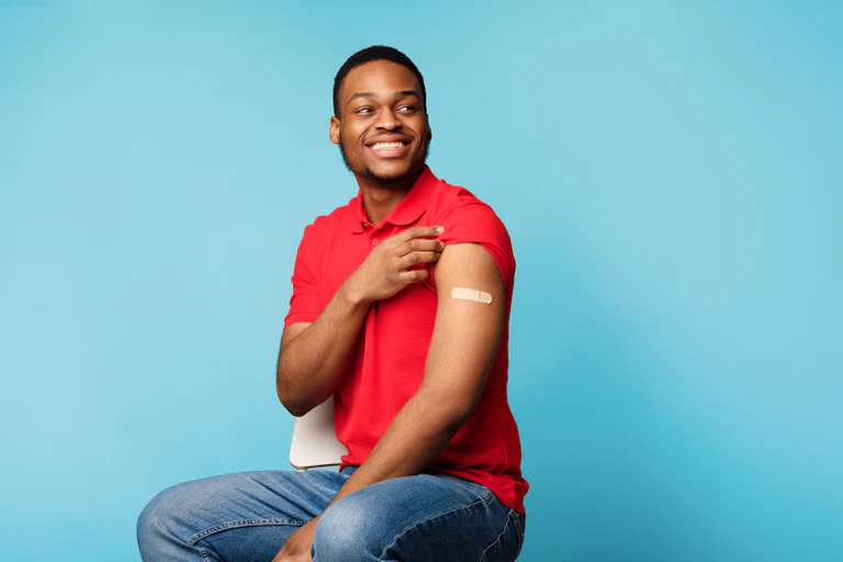 Person of colour showing off vaccination plaster on arm