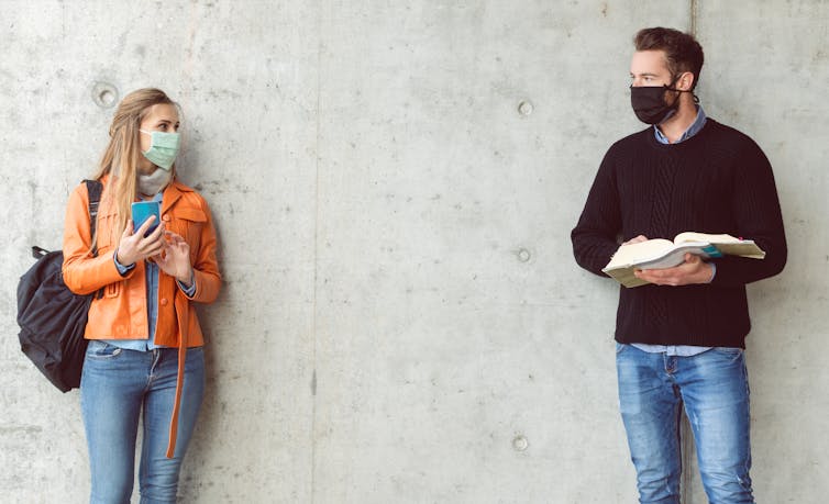 A man and a woman on a university campus wearing masks