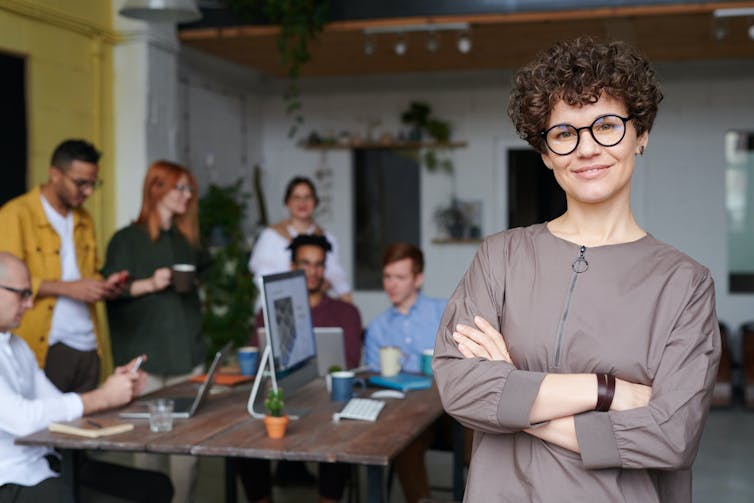 Office concept with woman wearing glasses in forefront.