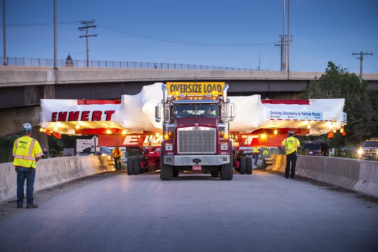 A truck carrying a much wider cargo down a road.