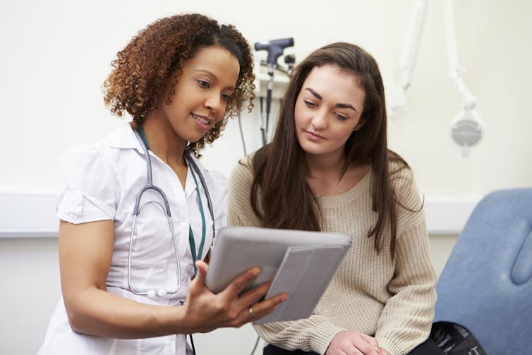 A doctor shows a patient information on a tablet