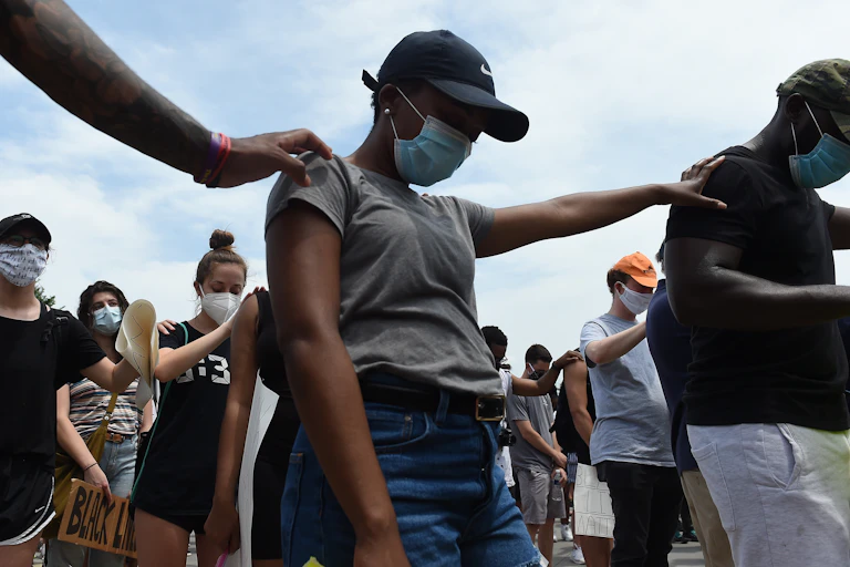 Protesters stand with hands on each others' shoulders