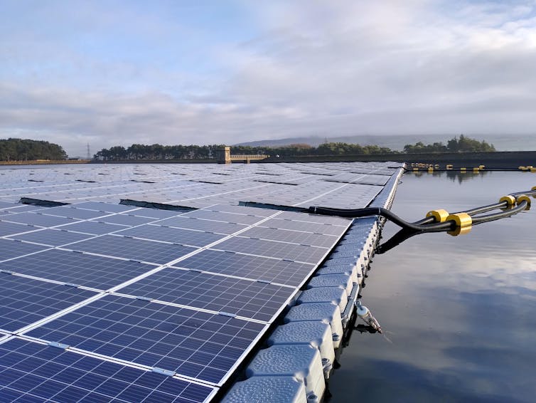 A raft of solar panels held in place on a reservoir's surface with a mooring rope.
