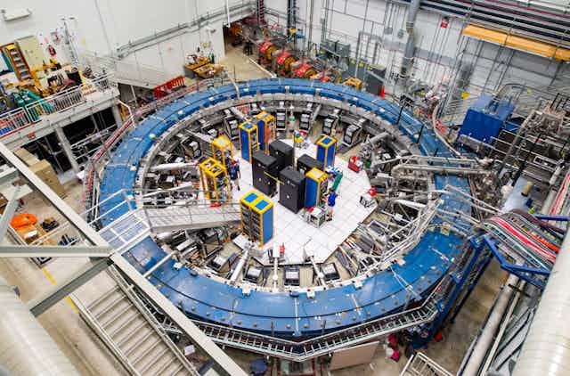 The muon experiment from above, showing a large blue ring surrounded by equipment.