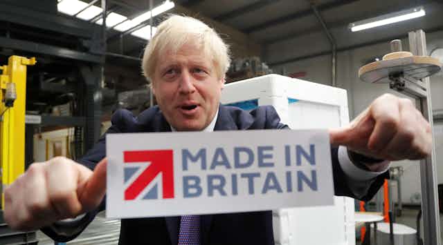 Boris Johnson sticking a 'Made in Britain' sticker on a window.