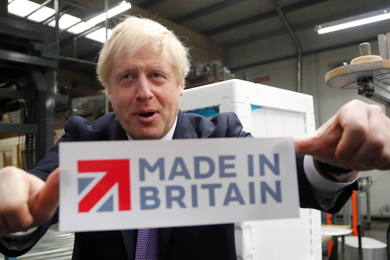 Boris Johnson sticking a 'Made in Britain' sticker on a window.