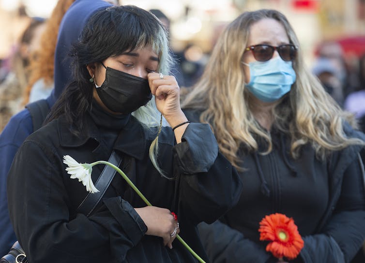 A woman sheds a tear holding a flower