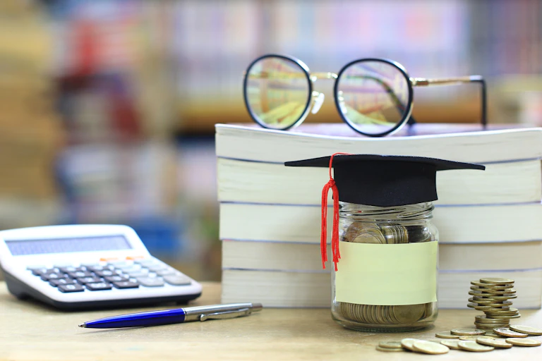 Glasses next to a calculator and coin savings.