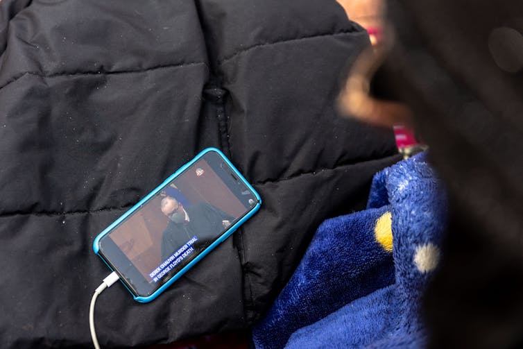 An activist watching the trial on a cellphone outside the government building in Minneapolis where the trial is taking place.