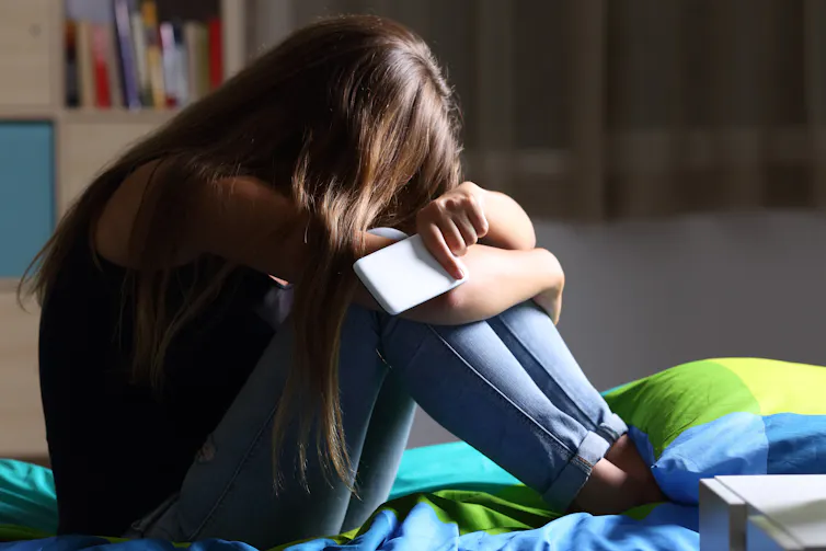 Sad girl holding mobile phone.
