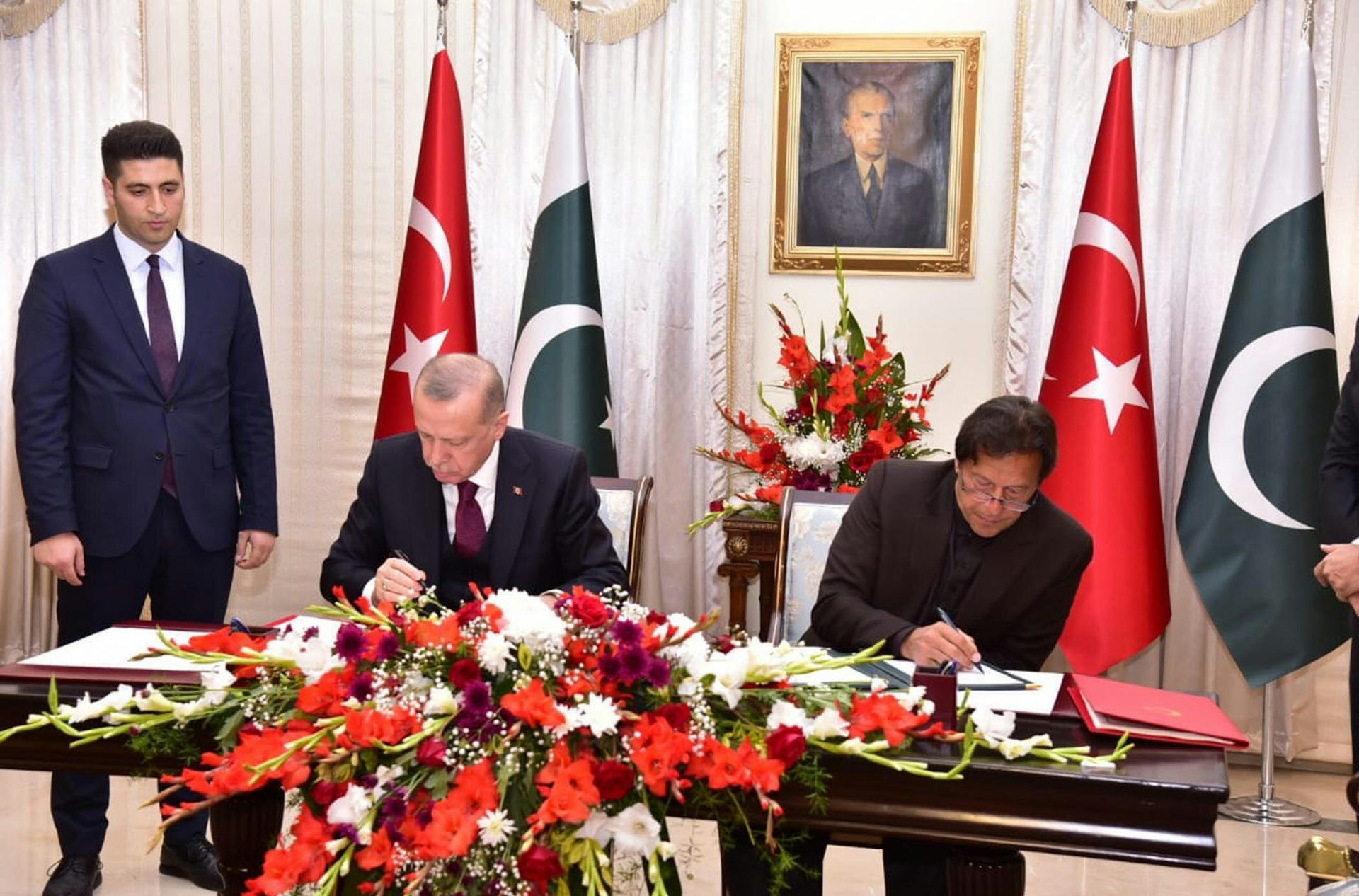 Turkish president Recep Tayyip Erdoğan and Pakistani president Imran Khan sitting at a table with Turkish and Pakistani flags in the background, signing a trade agreement, Islamabad, February 2021.