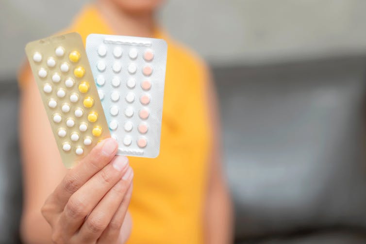 A woman holding two blister packs of oral contraceptive pills