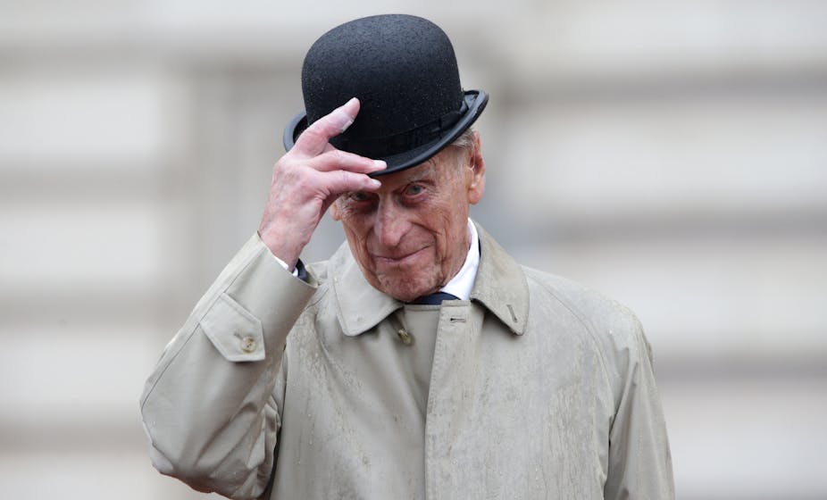 Le prince Philip portant et faisant basculer un chapeau melon.
