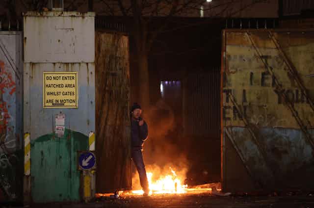 A man standing next to a fire during unrest in Northern Ireland.