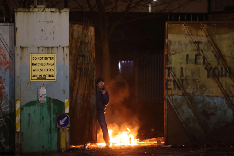A man standing next to a fire during unrest in Northern Ireland.