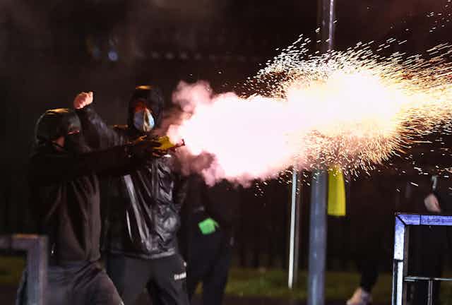 A young man shoots a firework during unrest in Belfast. 