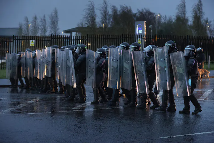 A line of riot police with shields.