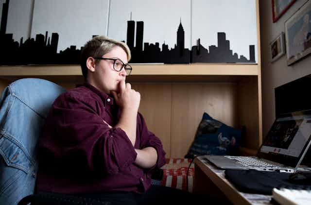 Trans male student sits at desk in front of laptop