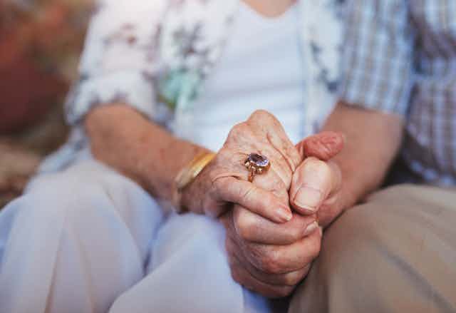 Close-up of clasped hands of an older man and an older woman