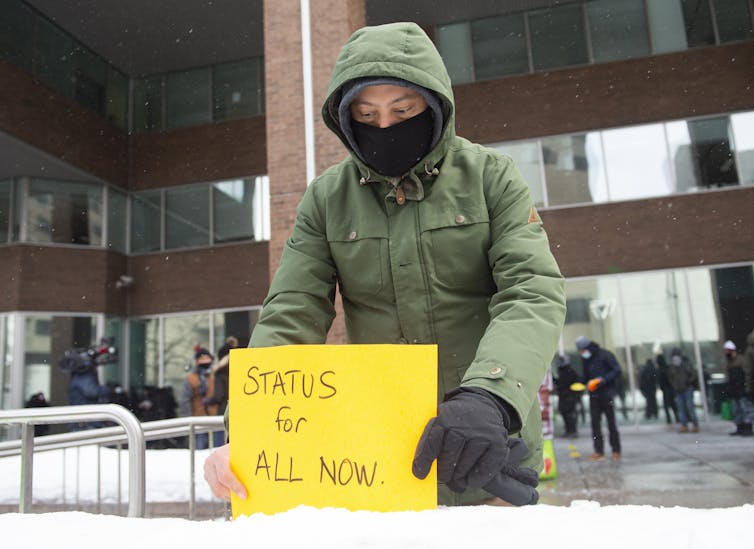 Man puts sign in snow that reads 'status for all'
