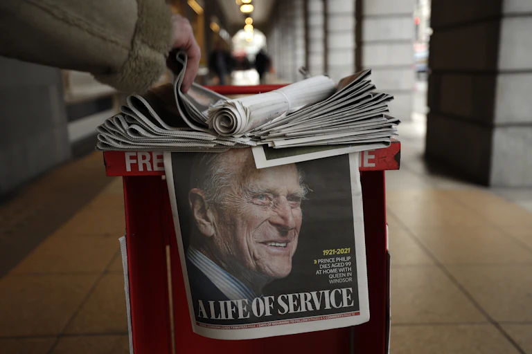 A man grabs a newspaper with a tribute to Prince Philip on the front page.