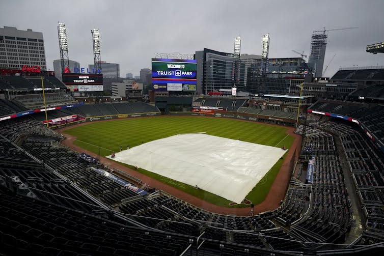 Rain falls onto Truist Park in Atlanta Georgia, where the Braves play baseball, as a tarp covers the infield