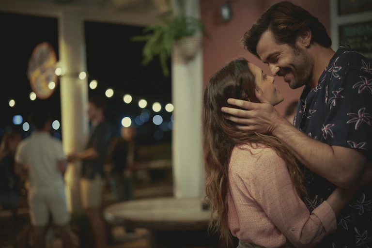 A couple lean in to kiss