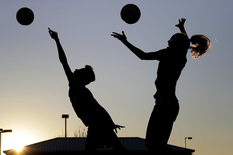 Two teenagers practicing volleyball.