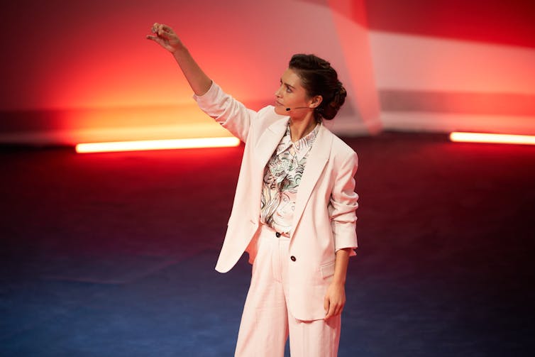 A woman on stage, looking at a vial