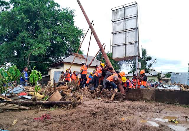 Workers raise an electricity pole after floods