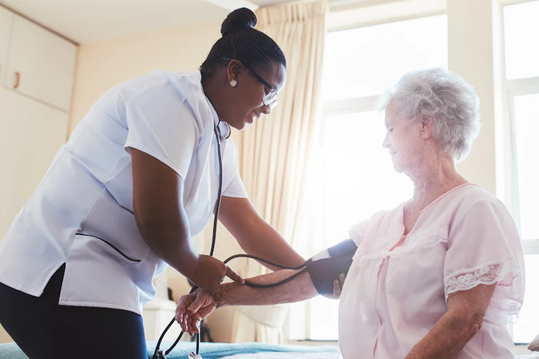 Female care worker check elderly woman's blood pressure.