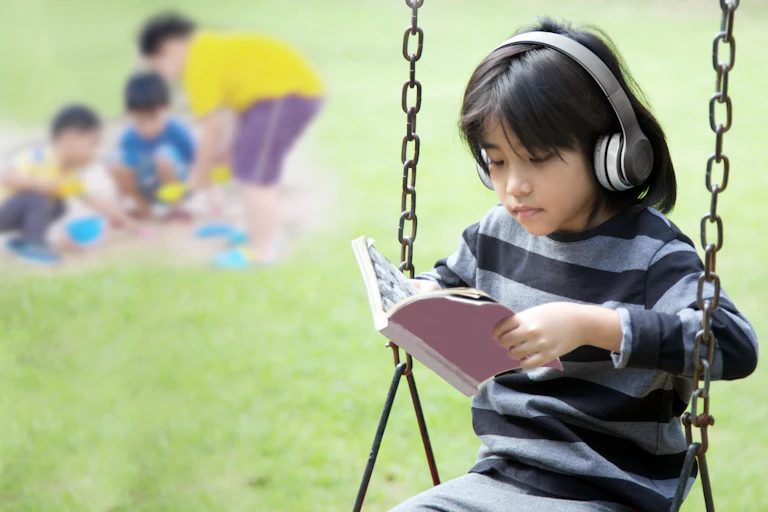 A girl wearing headphones on a swing in front of three children playing