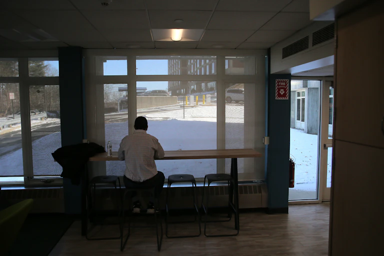 A college student sits alone, looking out onto an empty campus.