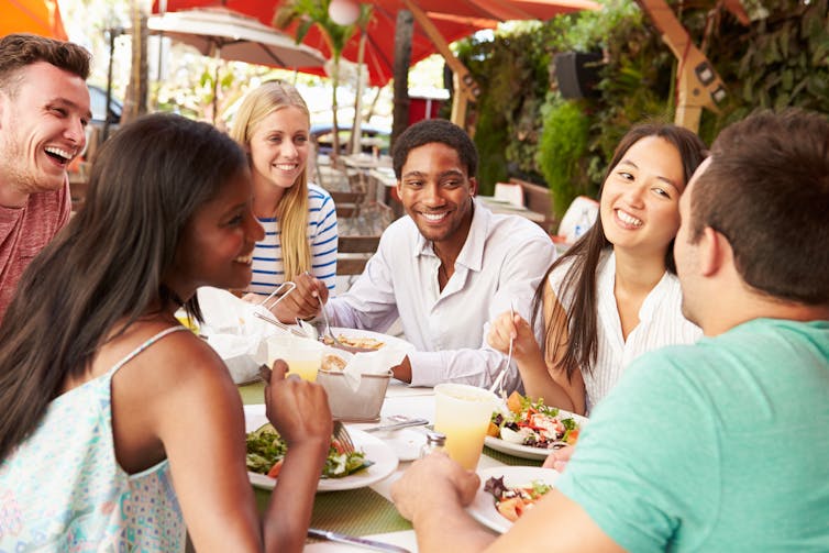 A group of people around an outdoor restaurant table, eating