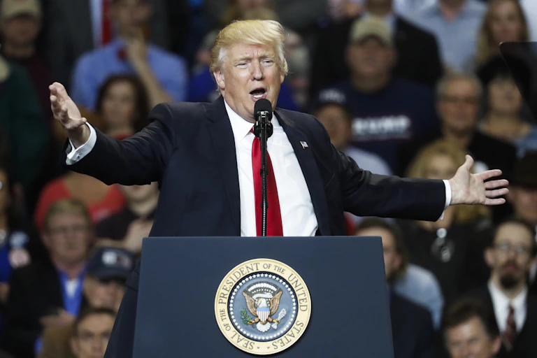 Donald Trump gesturing with arms spread wide during a rally in Louisville, Kentucky in 2017.