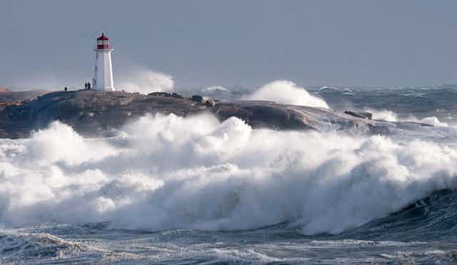 High surf and big waves with the Peggy's Cove lighthouse in the background.