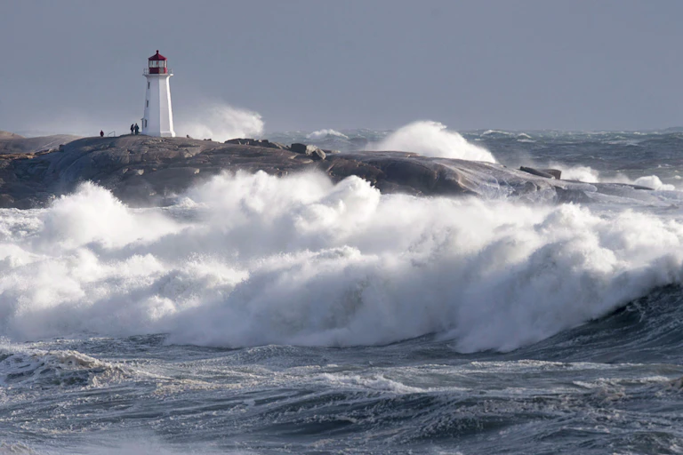 High surf and big waves with the Peggy's Cove lighthouse in the background.