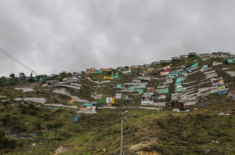 A green hillside with shacks on it