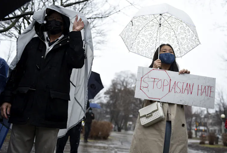 Woman stands holding sign that says 'Stop Asian Hate'